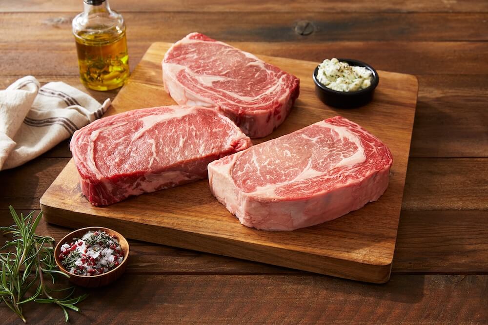 high marbling steak on a cutting board with seasonings on the side
