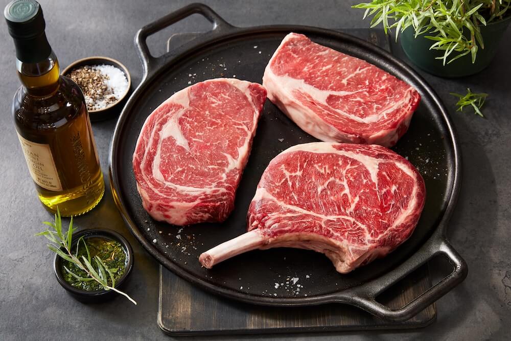 steak with fine marbling ready to be prepared on a dark serving plate and garnish on the side