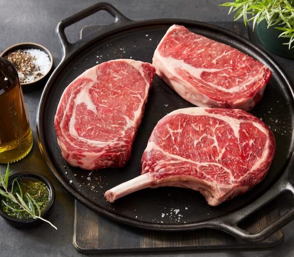 est-8-angus steak with fine marbling ready to be prepared on a dark serving plate and garnish on the side